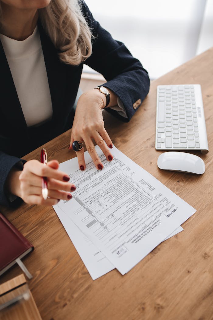 Close-up of a professional examining tax documents on a wooden desk indoors.